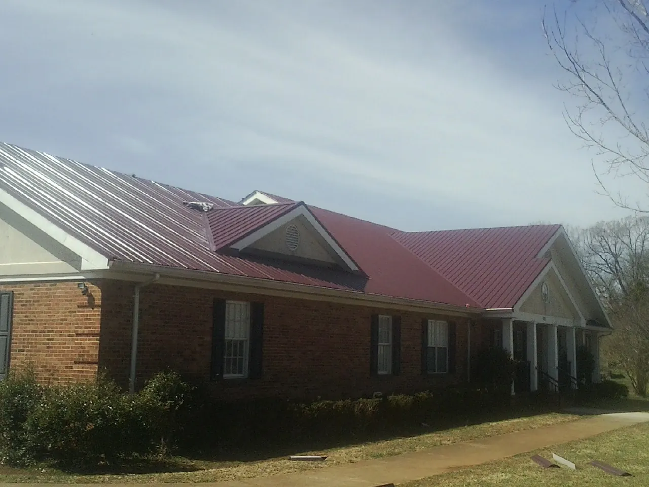 Red metal roof with gabled entries on a long brick building in Amanda