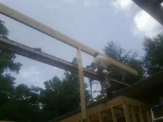 Carpenter setting a ridge beam over a new addition frame — Ice Dam Removal by Roofing Brothers in Amanda
