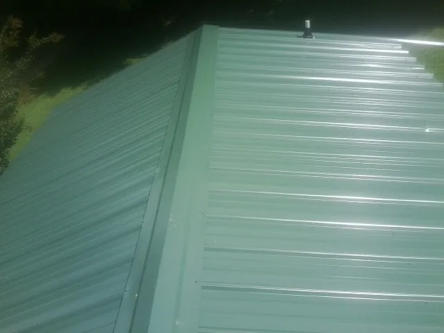 New green metal panels meeting at the ridge of a roof — Flat Roof Repair work by our crew in Amanda