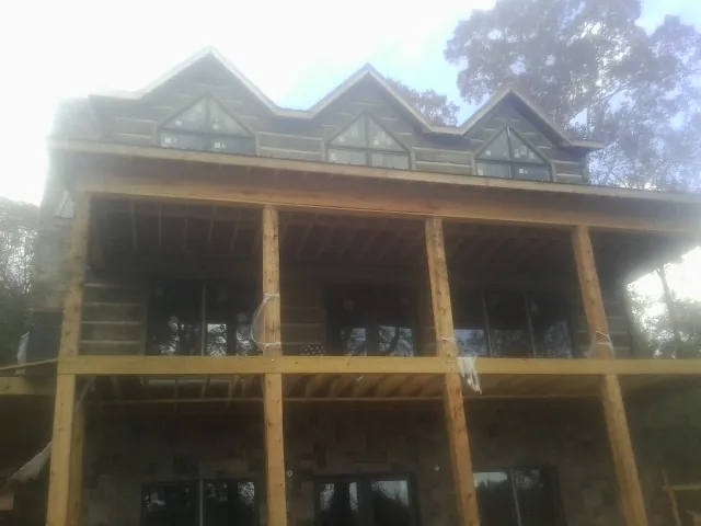 Dormers and porch framing on a large log home under construction — Roof Coating work by our crew in Amanda