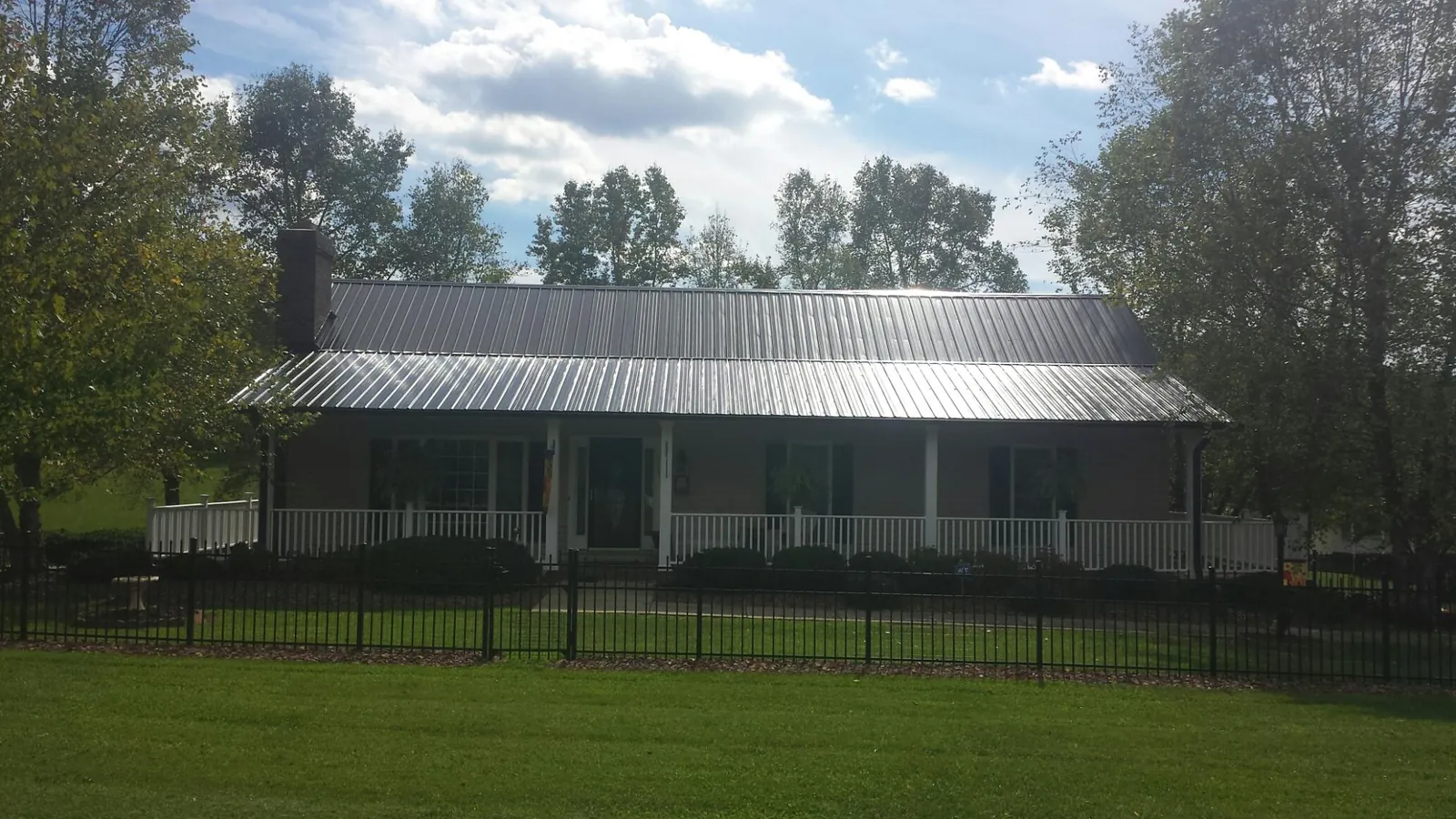 Gray metal roof on a brick ranch with a full width front porch — Gutter Guard Installation work by our crew in Amanda