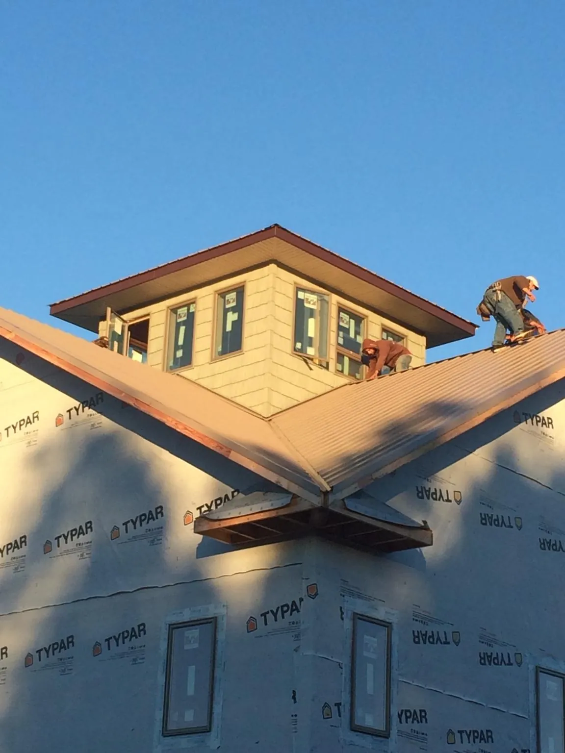 Roofers working around a rooftop cupola on a new metal roof at sunset — Roof Waterproofing in Amanda by Roofing Brothers